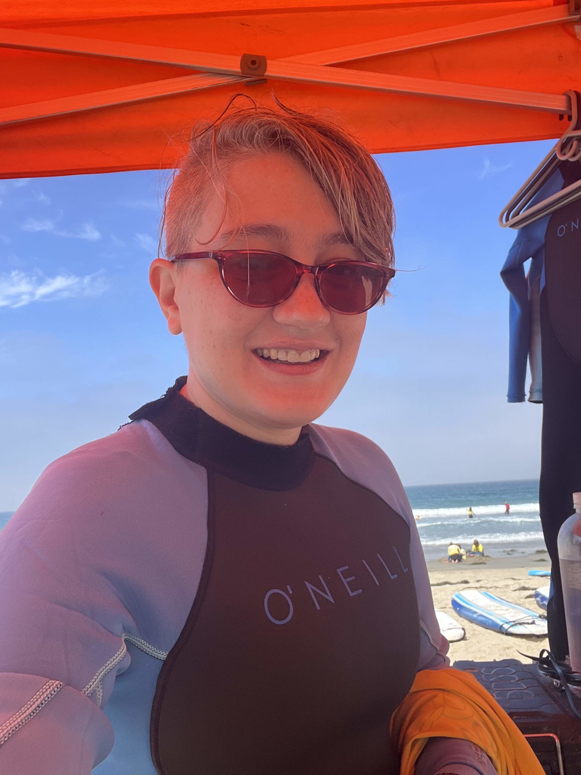 Becky (me), wearing a wetsuit and sunglasses, preparing for a surfing class