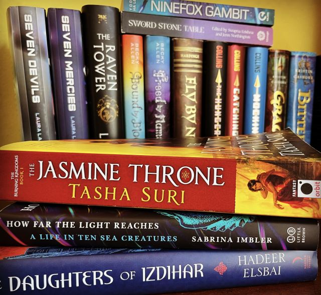 A stack of books, focused around The Jasmine Throne by Tasha Suri